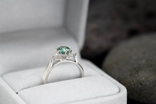 A single ring with a green stone set in a jewellery holder.